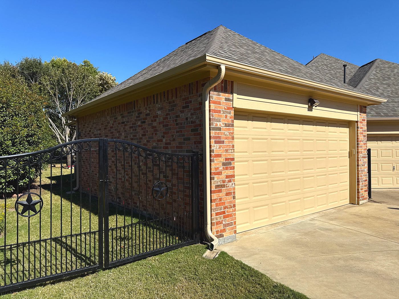 Recently completed roof and gutter replacement on a brick garage in Garland, the kind of permitted, warrantied work a legitimate local roofer stands behind