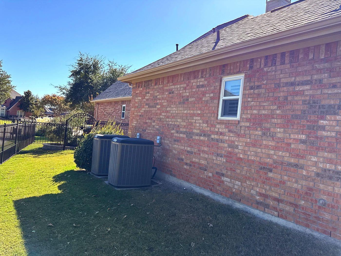 Side view of a finished shingle roof replacement on a brick home in Garland, TX